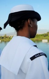 A sailor stands at attention as the USS Nimitz enters Pearl Harbor.